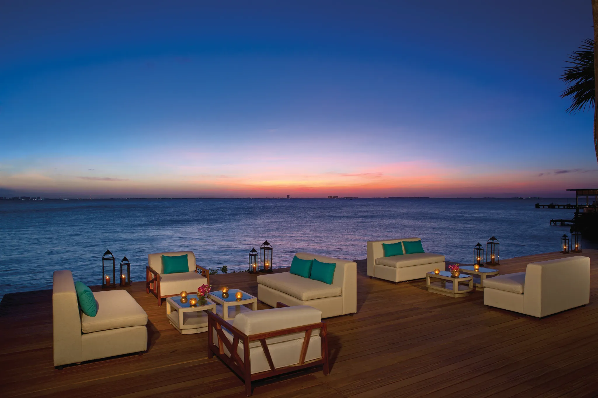 Oceanfront sunset lounge with cushioned seating and candlelight at Zoëtry Villa Rolandi Isla Mujeres, offering a serene Caribbean evening setting.